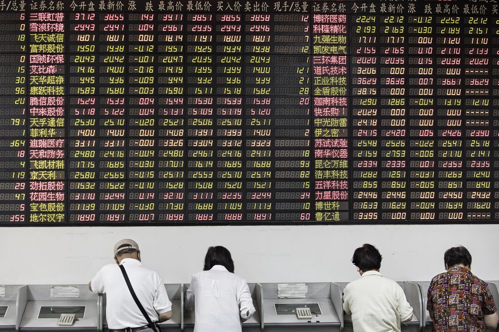Investors stand at trading terminals in front of an electronic stock board at a securities brokerage in Shanghai